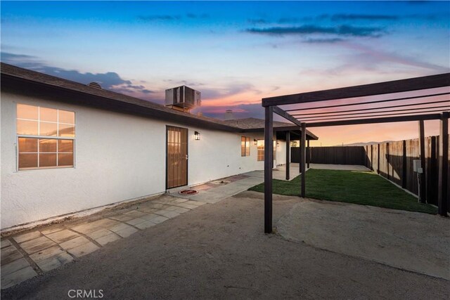 patio terrace at dusk featuring central air condition unit and a yard