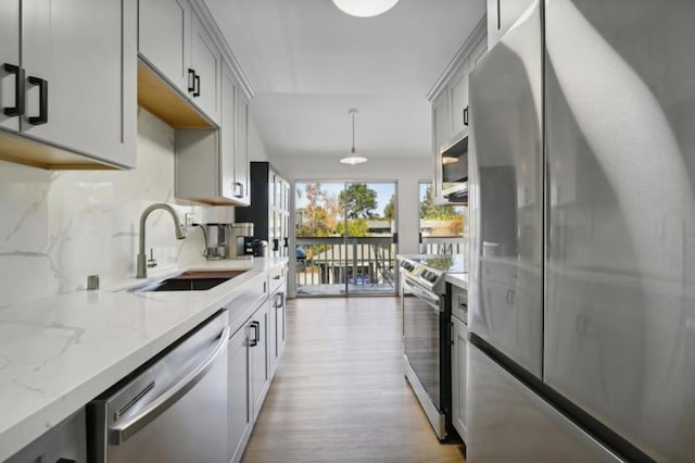 kitchen featuring decorative light fixtures, stainless steel appliances, gray cabinets, and sink