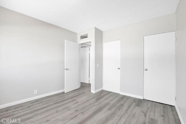 unfurnished bedroom with light hardwood / wood-style flooring and a textured ceiling