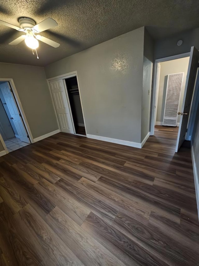 unfurnished bedroom with ceiling fan, a textured ceiling, dark hardwood / wood-style flooring, and a closet