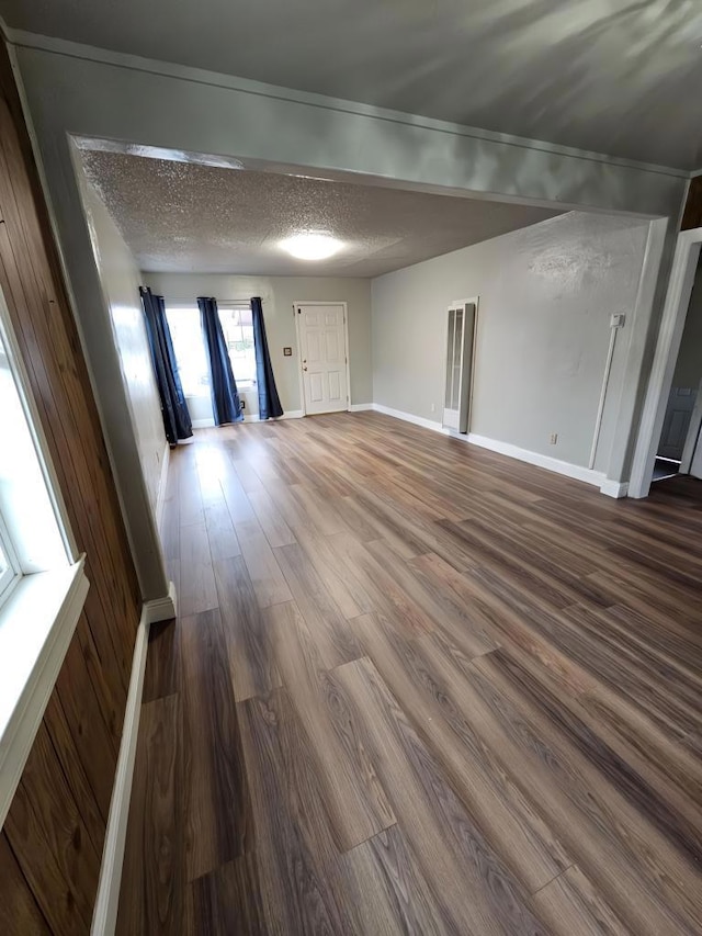 unfurnished living room with a textured ceiling and dark hardwood / wood-style floors