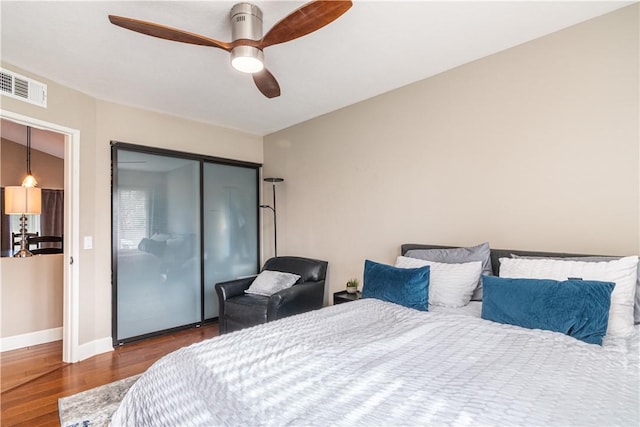 bedroom with ceiling fan, dark wood-type flooring, and a closet