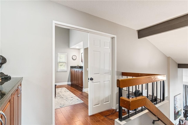 corridor featuring hardwood / wood-style floors, lofted ceiling with beams, and a textured ceiling