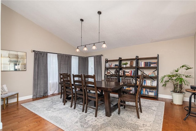 dining space featuring wood-type flooring and high vaulted ceiling