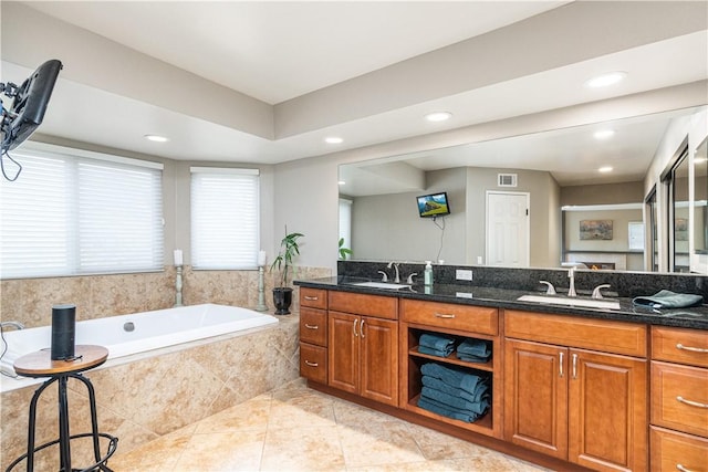 bathroom featuring tile patterned floors, vanity, and tiled bath