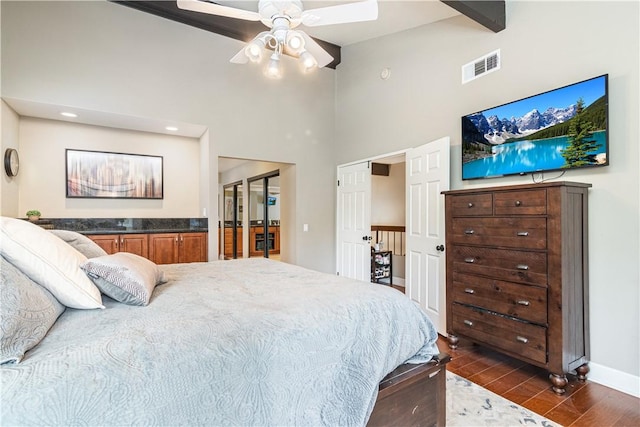 bedroom featuring a high ceiling, dark hardwood / wood-style floors, ceiling fan, and beam ceiling