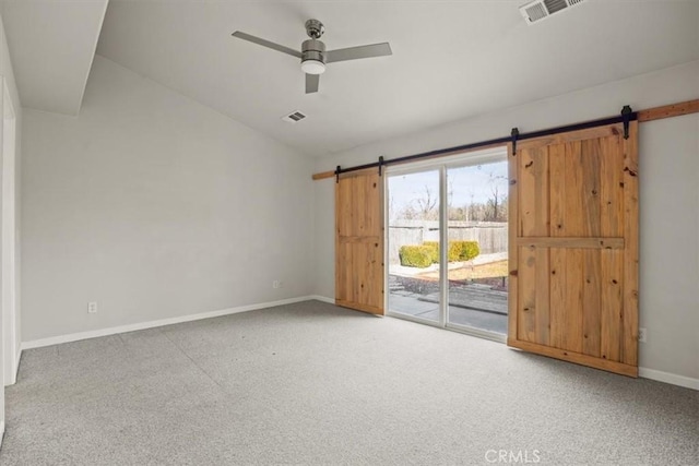 spare room with visible vents, a ceiling fan, a barn door, baseboards, and vaulted ceiling