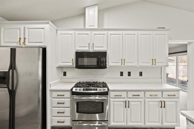 kitchen featuring vaulted ceiling, appliances with stainless steel finishes, and white cabinets