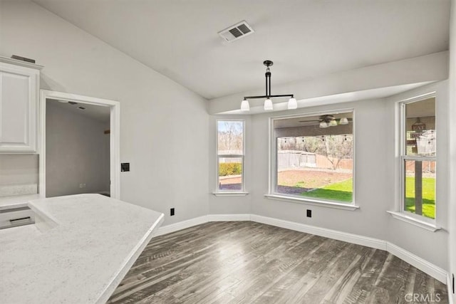 unfurnished dining area with ceiling fan, vaulted ceiling, and dark hardwood / wood-style flooring