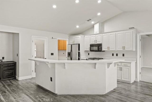 kitchen with stainless steel refrigerator with ice dispenser, a large island with sink, a kitchen bar, and white cabinetry