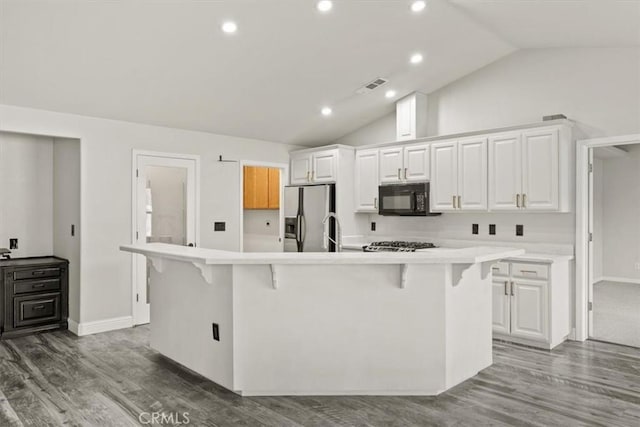 kitchen with stainless steel fridge, white cabinetry, light countertops, and black microwave