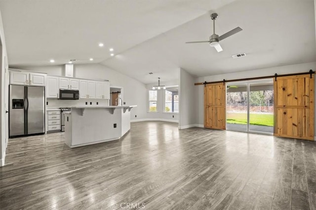 living room with a barn door, wood finished floors, a ceiling fan, and vaulted ceiling