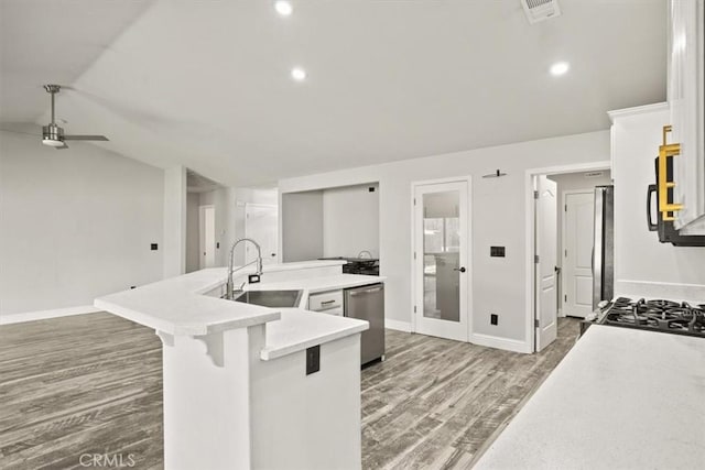 kitchen featuring a ceiling fan, a sink, a spacious island, dishwasher, and vaulted ceiling