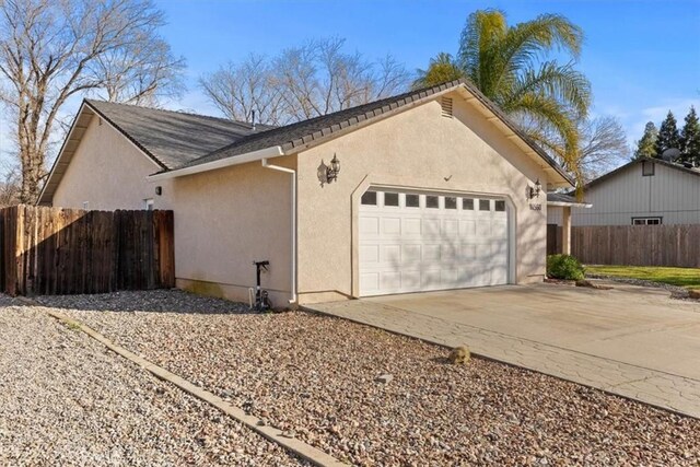 garage with concrete driveway and fence