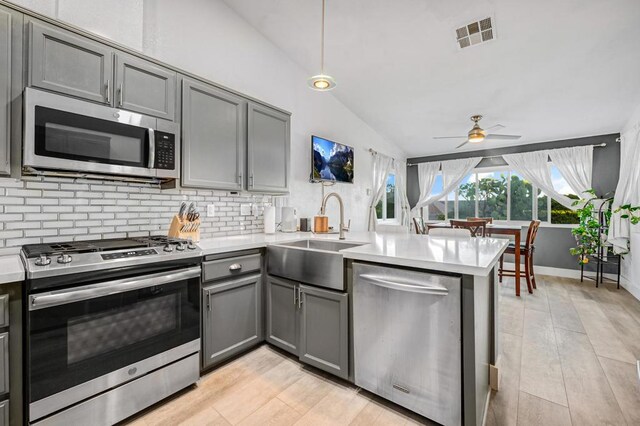 kitchen with gray cabinetry, kitchen peninsula, sink, and appliances with stainless steel finishes