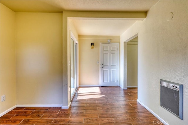 hall featuring heating unit, beamed ceiling, and dark wood-type flooring