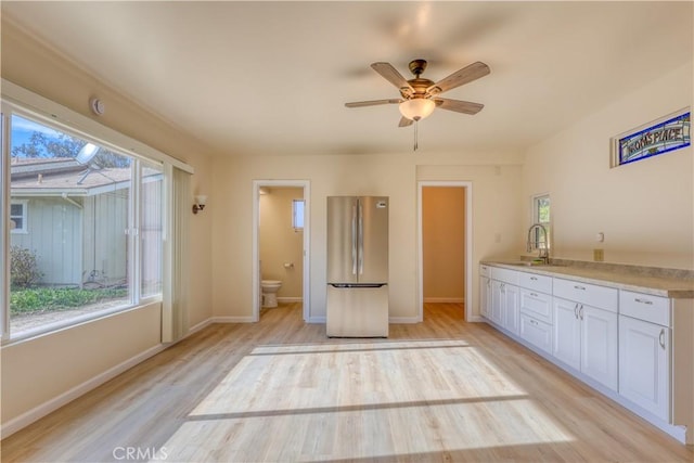 kitchen featuring ceiling fan, sink, stainless steel fridge, light hardwood / wood-style floors, and white cabinets