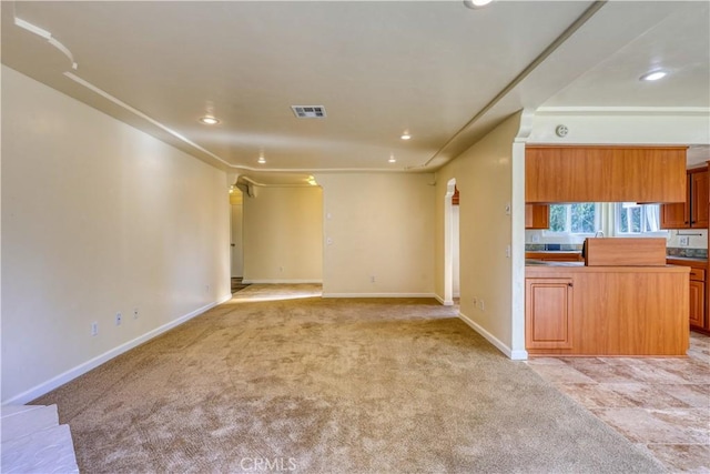 unfurnished living room with light colored carpet and ornamental molding