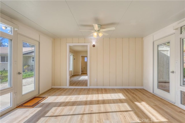 spare room featuring ceiling fan, a healthy amount of sunlight, and light hardwood / wood-style flooring