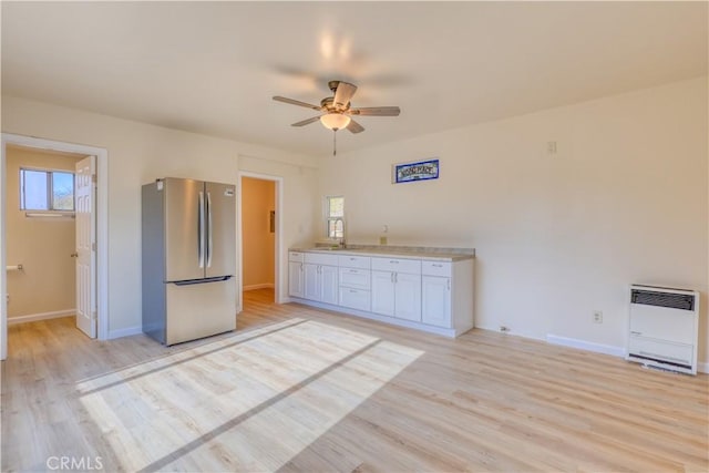 kitchen featuring stainless steel fridge, heating unit, white cabinetry, and light hardwood / wood-style flooring