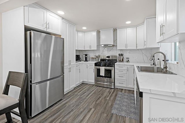 kitchen featuring wall chimney exhaust hood, light stone countertops, dark hardwood / wood-style flooring, white cabinetry, and stainless steel appliances