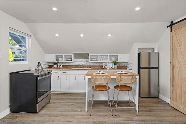 kitchen with sink, stainless steel appliances, a barn door, white cabinets, and light wood-type flooring