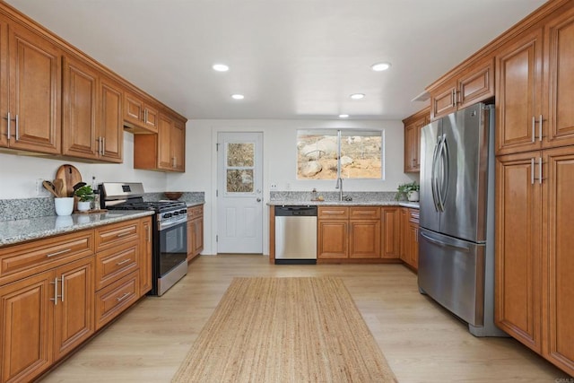 kitchen featuring light hardwood / wood-style floors, sink, light stone counters, and stainless steel appliances