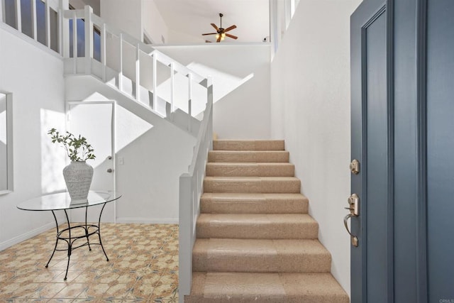 stairway with ceiling fan and a high ceiling