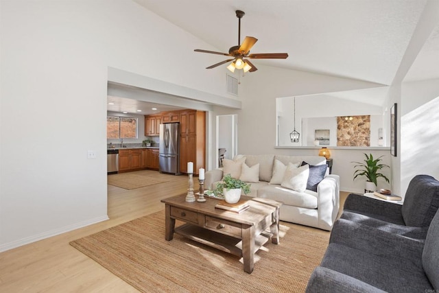 living room with ceiling fan, high vaulted ceiling, sink, and light hardwood / wood-style floors