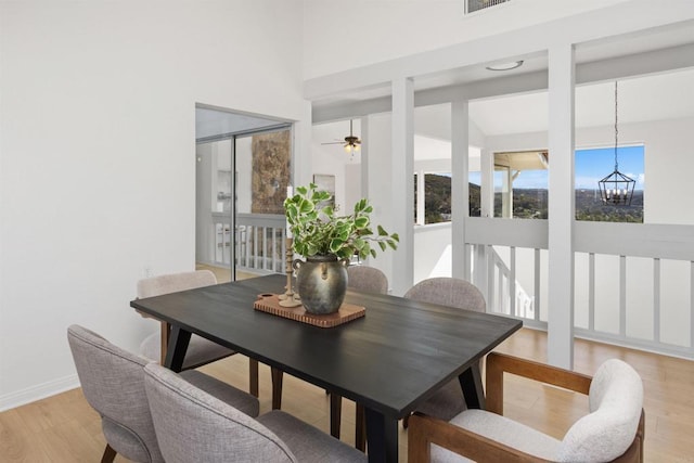 dining room with ceiling fan with notable chandelier and light hardwood / wood-style floors