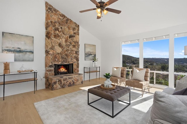 living room featuring a fireplace, ceiling fan, high vaulted ceiling, light wood-type flooring, and a mountain view