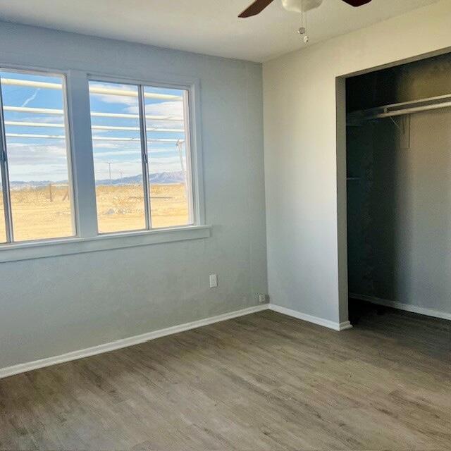 unfurnished bedroom featuring ceiling fan, wood-type flooring, and a closet