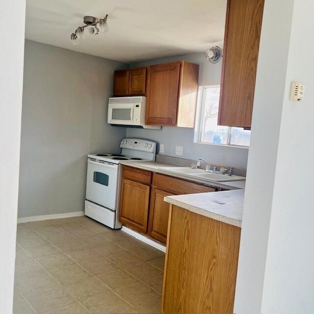 kitchen with white appliances, sink, and light tile patterned floors