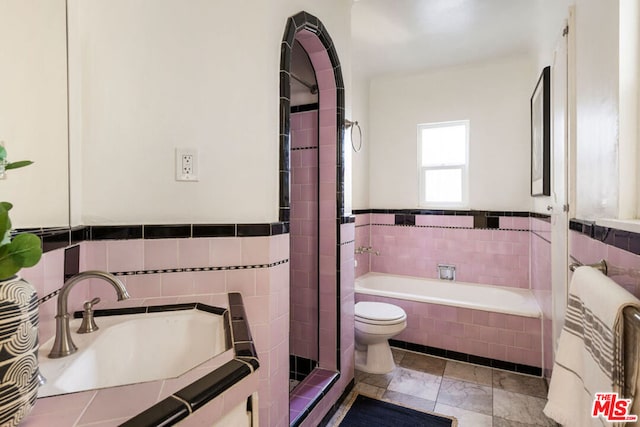 bathroom featuring sink, a relaxing tiled tub, and toilet