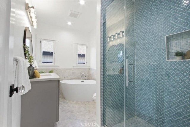 bathroom with tile patterned floors, vanity, independent shower and bath, and tile walls