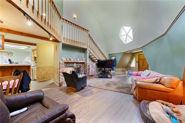 living room featuring beamed ceiling, light hardwood / wood-style flooring, a towering ceiling, and a fireplace