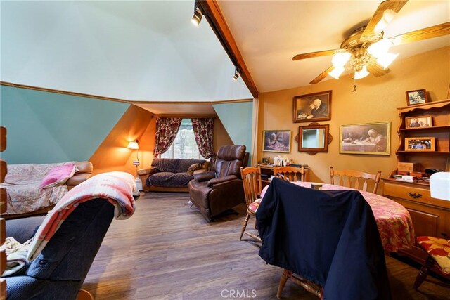 bedroom featuring ceiling fan, vaulted ceiling with beams, wood-type flooring, and rail lighting