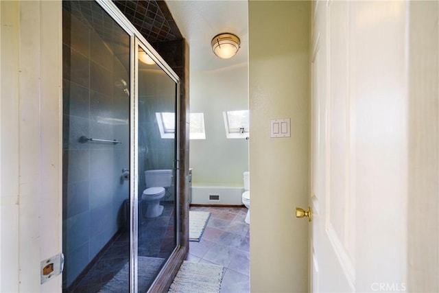 bathroom featuring toilet, tile patterned flooring, and a shower with shower door