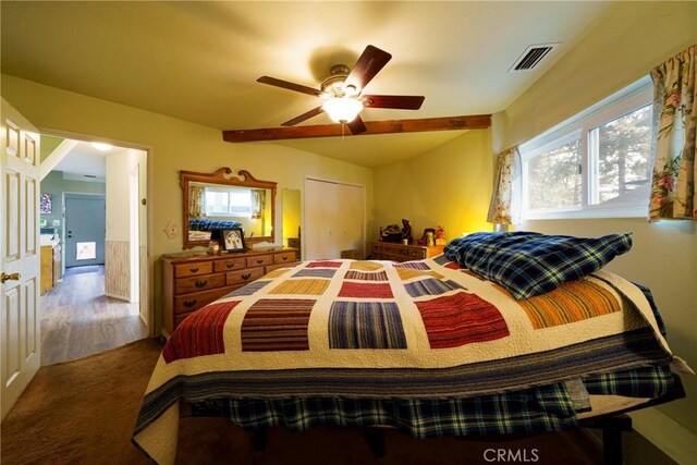 carpeted bedroom with ceiling fan, a closet, and beam ceiling