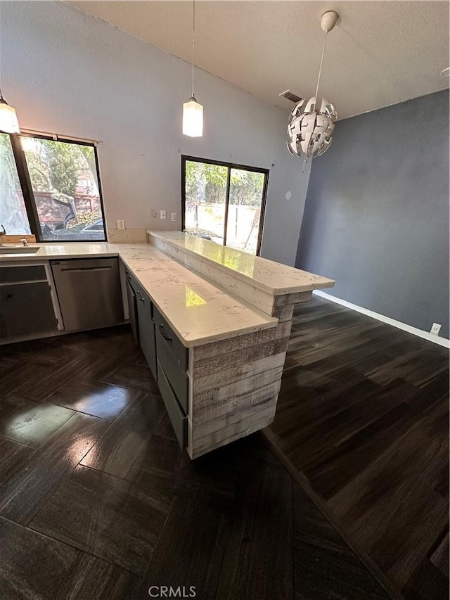 kitchen featuring pendant lighting, lofted ceiling, stainless steel dishwasher, a notable chandelier, and kitchen peninsula