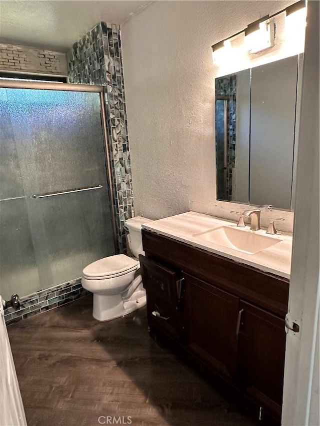 bathroom featuring hardwood / wood-style floors, vanity, toilet, and a shower with door