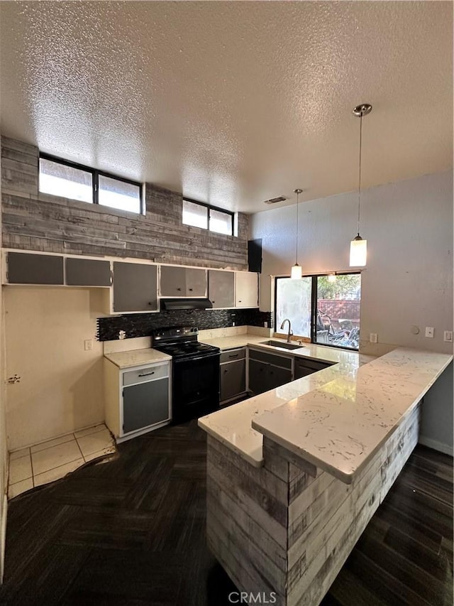 kitchen featuring kitchen peninsula, a textured ceiling, black range with electric cooktop, and hanging light fixtures