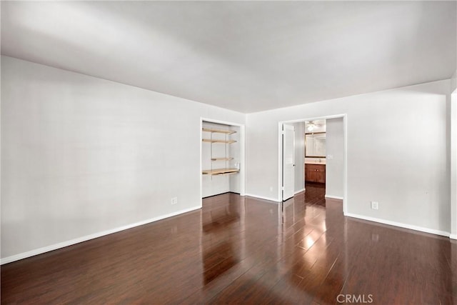 unfurnished room featuring baseboards and dark wood-style flooring