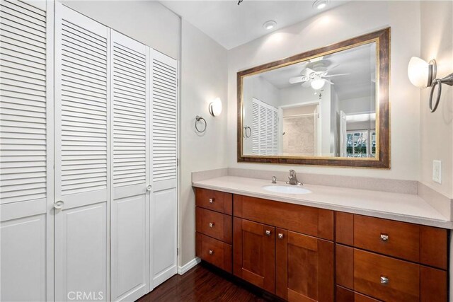 bathroom with a closet, ceiling fan, vanity, and wood finished floors