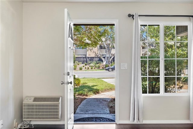 doorway to outside featuring a wealth of natural light and an AC wall unit