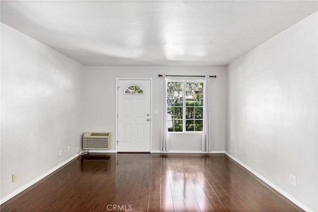 foyer with dark wood-style floors, a wall mounted AC, and baseboards