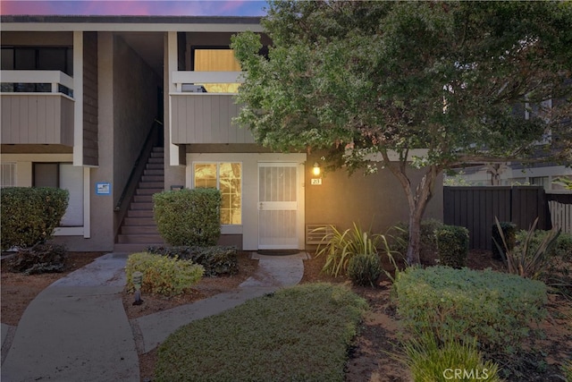 entrance to property with fence and stucco siding