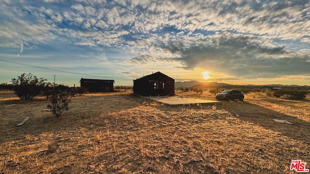 yard at dusk featuring a mountain view and a rural view