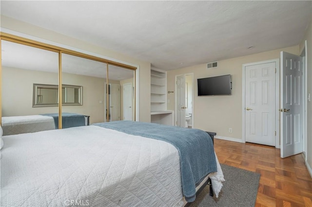 bedroom with dark parquet floors and a closet