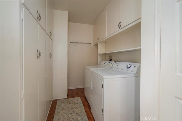 clothes washing area with washer and dryer, dark hardwood / wood-style flooring, and cabinets